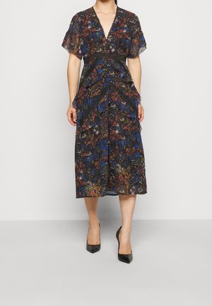Robe midi à imprimé floral en tissu sombre avec volants, décolleté en V et manches courtes ; associée à des escarpins noirs à bout pointu.