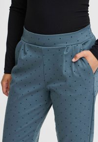 Türkise Baumwollmischungshosen mit einer glatten Textur, die ein gepunktetes Muster und seitliche Taschen aufweisen, gestaltet mit einem breiten, elastischen Bund.