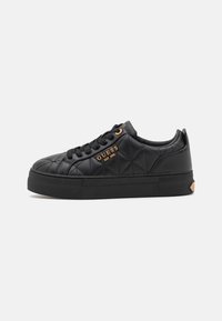 Sorte quilted sneakers med en flad gummisål, udstyret med sorte snørebånd, guld accenter og et logo på siden.