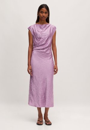 Lila midi-jurk met kapmouwen, gedrapeerde textuur en een licht gekreukelde afwerking. Draagt met eenvoudige zwarte platte sandaal.