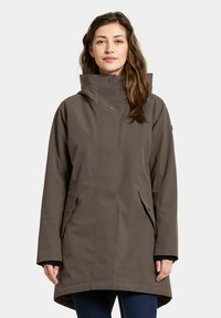 Braune wasserdichte Jacke mit hohem Kragen, Knopfakzenten, seitlichen Taschen und geradem Schnitt. Der Stoff wirkt glatt und langlebig.