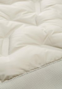 Weiße gepolsterte Matratzenauflage mit einer strukturierten grauen Unterseite. Verfügt über ein gequiltetes Muster und glattes Gewebe, das Weichheit und Komfort betont.
