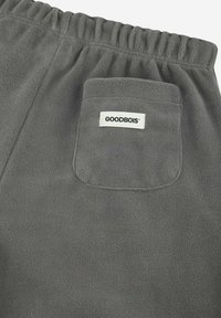 Graue Fleece-Jogginghosen mit einem elastischen Bund und einer Gesäßtasche mit einem weißen "GOODBOIS"-Label. Die Textur ist weich und plüschig.