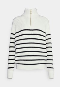 Suéter de punto a rayas blancas y negras con cuello alto, que presenta un detalle de cremallera dorada en el cuello y puños y dobladillo acanalados.