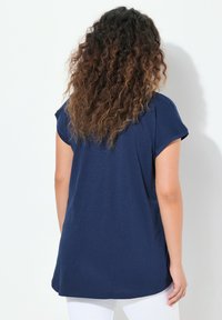 Marineblå t-shirt med korte ærmer, afslappet pasform og rund halsudskæring. Glat tekstur, lidt længere bagpå, minimeret design.