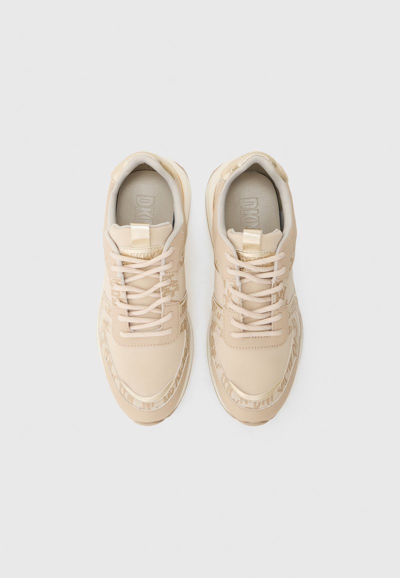 Beżowe sneakersy z gładką, syntetyczną cholewką, z ozdobnym sznurowaniem, teksturowanymi akcentami i subtelnym logo na języku, wyposażone w wyściółkę kołnierza dla większego komfortu.