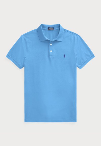 Polo bleu clair en coton, avec un col classique, des manches courtes, une patte de boutonnage à trois boutons, et un petit logo violet sur la poitrine.