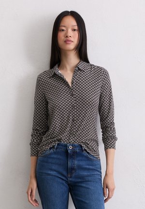 Camicia a maniche lunghe con colletto in tessuto marrone a fantasia, dal taglio morbido, abbinata a jeans blu, su sfondo neutro.