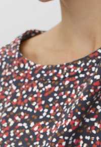 Námořnické šaty s kulatým výstřihem, zdobené multibarevným vzorem rozptýlených teček v červené, bílé a hnědé barvě. Měkká, strukturovaná tkanina.