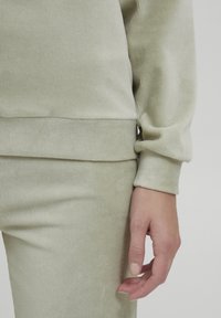 Set da lounge verde chiaro con texture a coste. La parte superiore ha una vestibilità comoda con maniche a giro, abbinata a pantaloni a coste coordinati.
