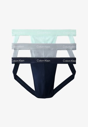 Tre Calvin Klein herre-jockstraps i hvid, grå og sort med mærket elastik i taljen stablet lodret.