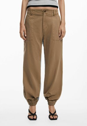 Brown wide-leg pants with a high waist, featuring front pockets and elasticized cuffs, paired with black strappy sandals.