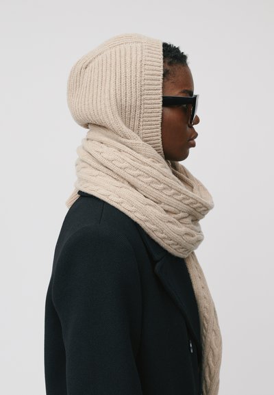 Ensemble de hoodie et écharpe en tricot de couleur abeille, avec une texture côtelée et un motif en maille torsadée. Le tissu est doux et chaud, dans une teinte beige clair.