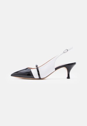 Chaussure à bride arrière noir et blanc à bout pointu, avec un petit talon chaton bas et une fine sangle traversant le cou-de-pied avec une petite boucle.