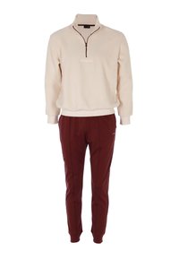 Pullover in pile color crema con zip a quattro punti e logo ricamato; abbinato a pantaloni della tuta color bordeaux con taglio affusolato, cuciture laterali e tasche.