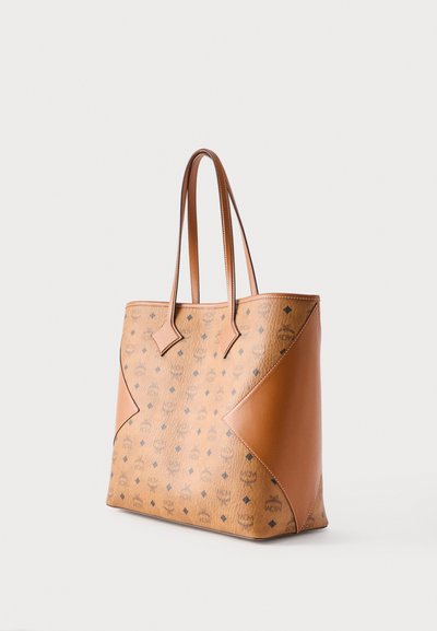 Τσάντα χειρός από δέρμα ταμπά με επαναλαμβανόμενα σκοτεινά μοτίβα λογότυπου, λείες δερμάτινες πλαϊνές επιφάνειες και δύο μακριές λαβές.