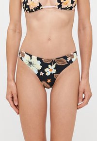 Fekete virágmintás bikini alsó, nagy pasztell virágokkal, zöld levelekkel és narancssárga akcentusokkal. Sima anyag, alacsony derékvonallal és minimális takarással.