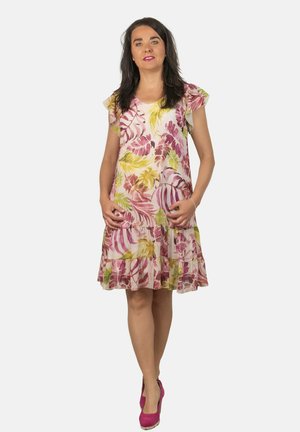 Un vestido floral en colores pastel que presenta mangas cortas con vuelo, un dobladillo en capas y un corte relajado, combinado con tacones rosas.