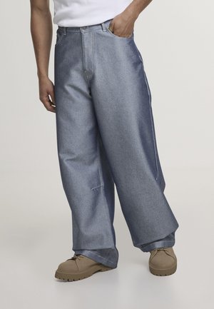 Lyseblå denimbukser med vide ben og høj talje, med sidelommer og kontrastfarvet syning. Bruges med beige sko.