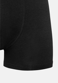 Boxer shorts neri in cotone con vestibilità aderente, caratterizzati da cuciture precise lungo i bordi e una texture liscia.
