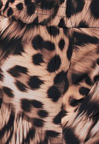 Látka se vzorem leopardí kožešiny, která kombinuje odstíny světle hnědé, tmavě hnědé a černé, s hladkou texturou a dynamickým vzorem po celé ploše.