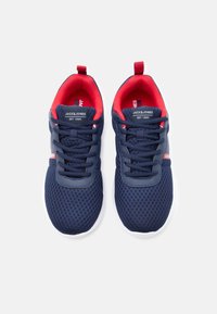 Ζευγάρι αθλητικών παπουτσιών από μπλε ναυτικό πλέγμα με κόκκινη εσωτερική επένδυση, λευκές σόλες, μαύρα κορδόνια και το λογότυπο «Jack & Jones» στη γλώσσα και τις πλευρές.