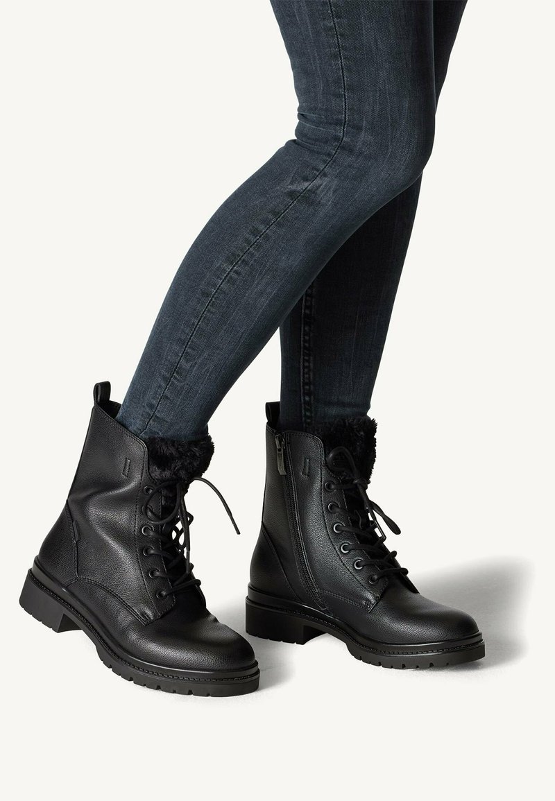 Botas negras hasta el tobillo con un acabado de cuero liso, forro interior suave, cordones en la parte delantera y cremallera lateral. Suela gruesa con relieve para mayor agarre.