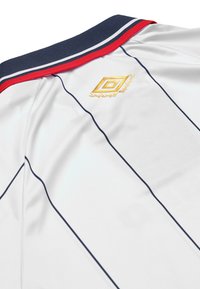 Maglia bianca con colletto blu navy, strisce rosse e bianche, dettaglio logo dorato e righe verticali blu. Tessuto dal tocco liscio.