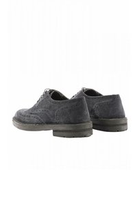 Le scarpe wingtip in suede grigio presentano una punta arrotondata, chiusura con lacci e dettagli testurizzati. La suola è nera con un design cucito.