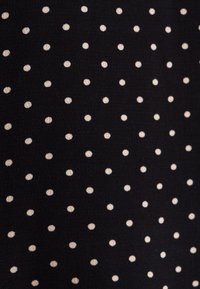 Tissu noir avec de petits pois blancs espacés régulièrement dans un motif en grille régulière.