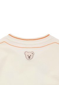 Col collier couleur crème avec des surpiqûres orange et un logo de tête d'ours doux et brodé au dos. Texture lisse.