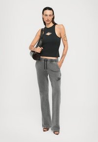 Black cropped tank top with a diamond cutout, paired with gray tapered sweatpants featuring an elastic waistband and embroidered logo detail.