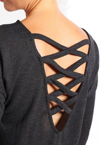 Top in maglia nera con una profonda scollatura a V sul retro e un intricato design di spalline incrociate. Tessuto liscio e materiale leggero.
