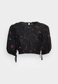 Blusa nera cropped con stampa floreale in viola e verde. Presenta maniche a palloncino e una chiusura con lacci sul retro. Tessuto leggero.