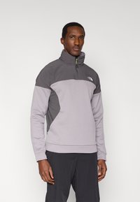 Gray quarter-zip sweatshirt with high collar, featuring a panel design and textured side details. Material appears soft and lightweight.
