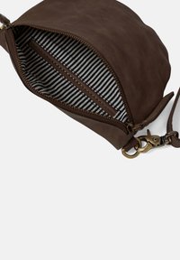 Hnědá kožená kabelka na ruku se zipovým uzávěrem, která má pruhovanou látkovou podšívku a mosazný klip na připevnění.