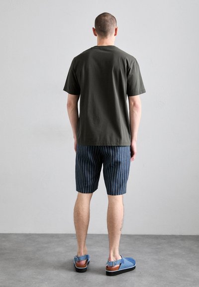 Oliven grøn bomulds T-shirt, navy stribede shorts, blå sandaler med brune accenter. Minimalistisk design, afslappet pasform og synlige sømme.