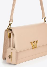 Borsa a tracolla in pelle crema con finitura texture, caratterizzata da un logo "W" in tonalità oro e un’etichetta rimovibile, completata da una sottile tracolla.