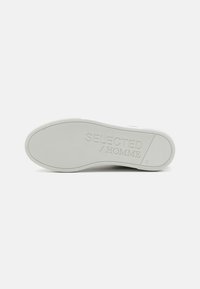 White sneaker sole with a textured rubber surface. Features embossed brand name "SELECTED / HOMME" and size "41." Simple design, clean lines.