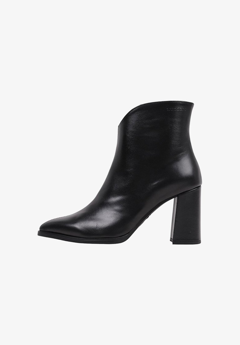 Bottine en cuir noir avec un bout pointu, un design structuré et un talon épais. Texture lisse et détails minimalistes.