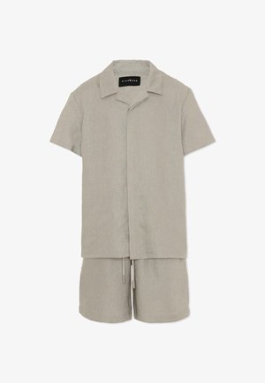 Chemise décontractée beige clair à manches courtes avec boutons, accompagnée d'un short à cordon assorti, fabriquée en tissu texturé.