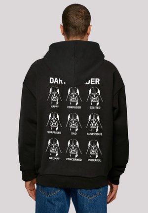 Svart hettegenser med et grafisk trykk av ni Darth Vader-ansikter i hvitt, hver merket med forskjellige følelser. Materialet ser mykt og avslappet ut.