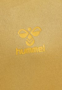 Tessuto giallo con una superficie testurizzata, caratterizzato da un logo debossed ben visibile di "hummel" e un design stilizzato di un'ape sopra di esso.