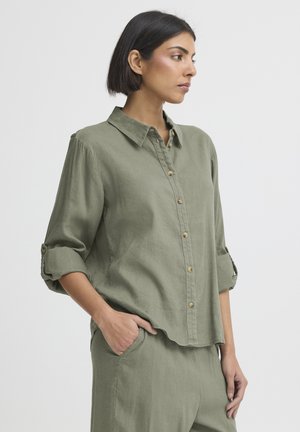 Ľanová košeľa olivovej zelenej farby s golierom, zapínaním na gombíky vpredu a vyhrnutými rukávmi. Má voľný strih a detail s náprsným vreckom.