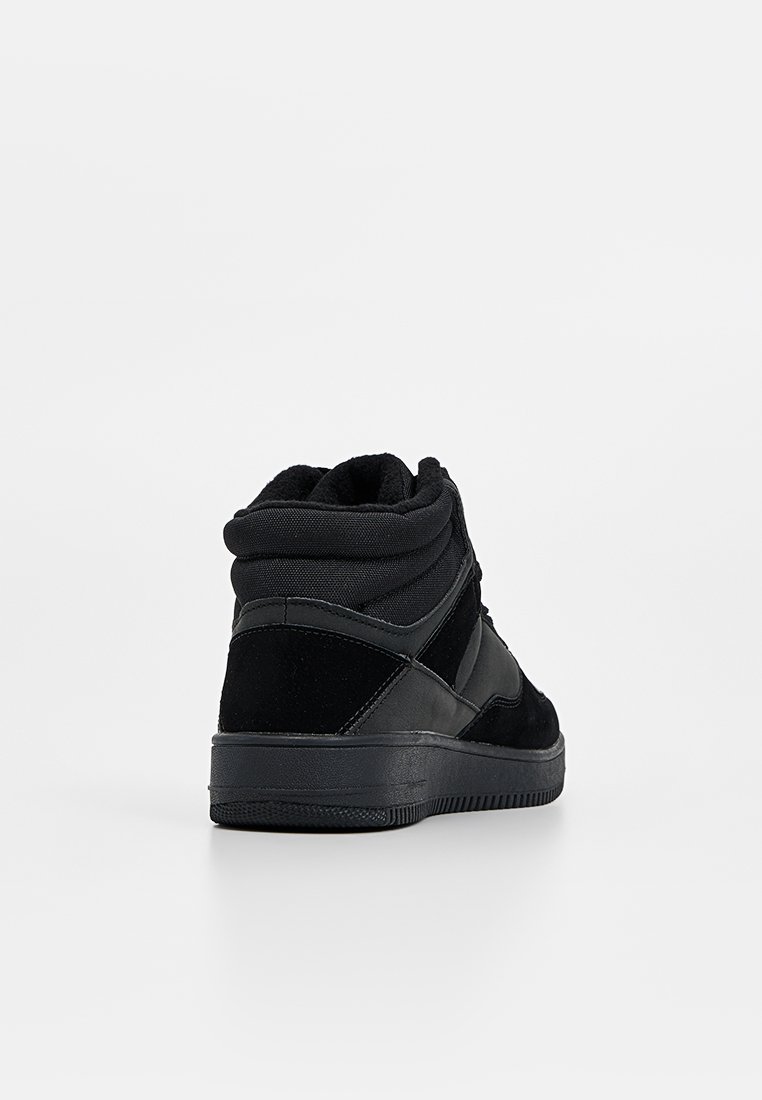 Zapatilla alta negra con materiales de ante y textil, cuello acolchado, suela de goma negra texturizada y sutil detallado del logotipo.