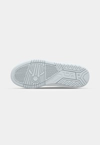 White sneaker sole with textured rubber pattern, featuring a circular design element and vertical and diagonal grooves for traction.
