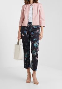 Ljust rosa läderjacka med rund krage, vit t-shirt, blommiga marinblå byxor, beige klackar och en vit axelväska.