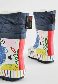 Bunte Gummistiefel mit einem marineblauen, gesteppten Schaft, einem auffälligen gemusterten unteren Teil mit gelben, blauen und grünen Designs und einer gestreiften Sohle.