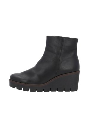 Stivali alla caviglia in pelle nera con una texture liscia, dotati di tacco a zeppa e di una suola spessa e scanalata. Design semplice con minimi dettagli.