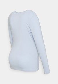 Camisa de manga longa azul-claro feita de um tecido suave, com decote redondo e silhueta ajustada, apresentando detalhes de costura mínimos.